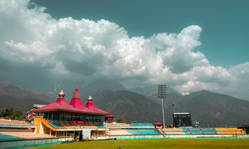 A cricket stadium nestled amidst majestic mountains.