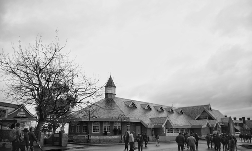 A monochrome image of individuals walking in front of a building.