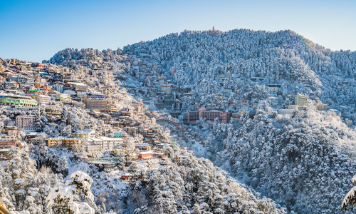 snow-covered Shimla cityscape, with buildings and trees blanketed in white, creating a serene winter scene.