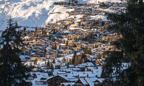 A charming snowy mountain village adorned with numerous houses in a tranquil winter setting.